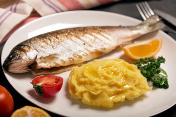 Grilled whole trout, potato, lemon and garlic, close up