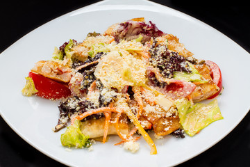 warm salad with cheese, fish, vegetables on a white plate