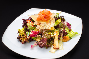 warm salad of fish, vegetables on a white plate