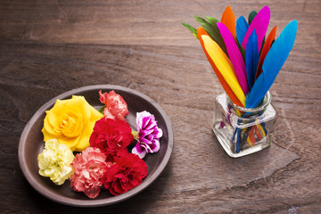 皿の上の花とボトルにさしたカラフルな羽根