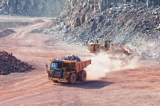 bulldozer loading dumper truck with porphyry rock material in a quarry