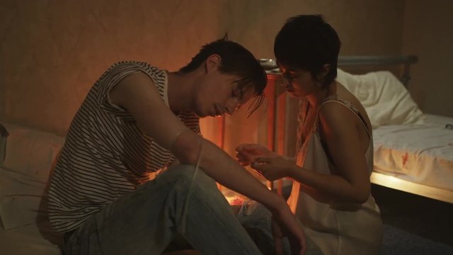  Drug addict couple in gloomy apartment taking heroin together