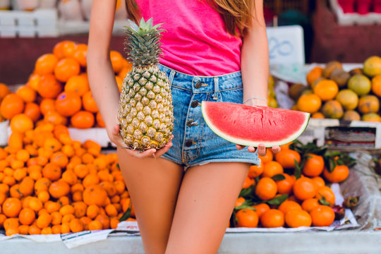 Ananas and slice of watermelon in hands of girl on tropical fruits background.