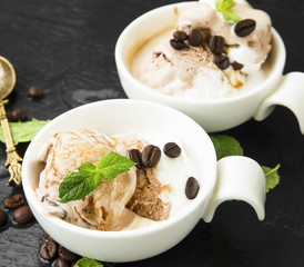 Coffee and vanilla ice cream scoops in cups with mint leaves