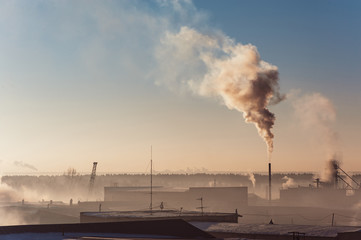 Industrial buildings in the fog on the blue sky backgrond. Warehouses. Smoke from the pipe. Smog.