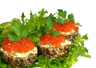 Three small sandwich with red caviar, made of black baguette, sprinkled with grains of cereals and poppy, lie on green lettuce leaves