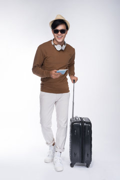 Full Length Of Young Tourist Asian Man Holding Passport With Suitcase Over Grey Background