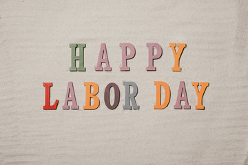 Happy Labor Day on the sandy beach background. Happy Labor Day word in colorful stones
