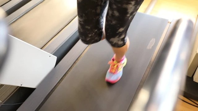 Slow motion of woman colorful shoes running on tapis roulant in gym. Fast training indoor. Aerial top view. Healthy active lifestyle concept.