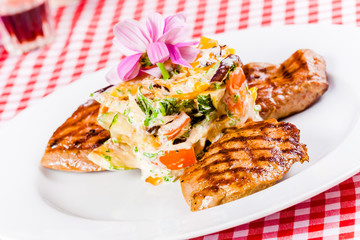 Grilled meat and vegetable salad on white plate