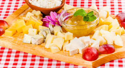 Assorted cheese with honey on wooden board