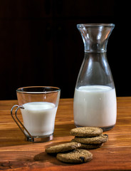 Bottle and glass of milk with cookies on a wooden table