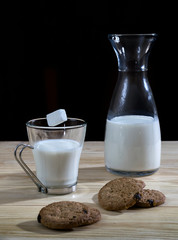 Crepes pancakes with honey and walnuts, milk glass and bottle and hand pouring powdered sugar on a wooden table