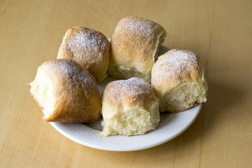 Five homemade traditional Czech buns stuffed with plum jam, raisins and cottage cheese on white plate on wooden table
