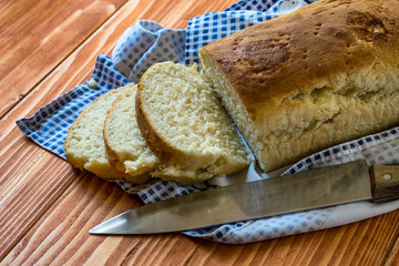 Sliced home made bread on a wooden table with a knife