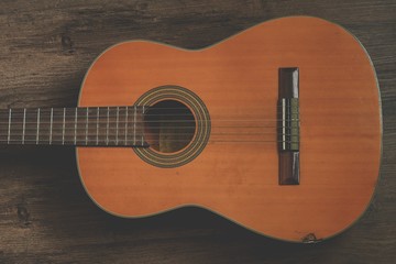 Vintage style closeup acoustic guitar on grunge wooden background