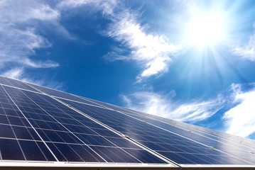 solar cell panel with strong sun and blue sky with clouds