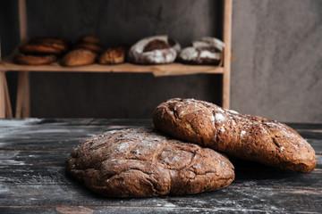 Bread with flour on dark wooden table at bakery
