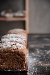 Bread with flour on dark wooden table
