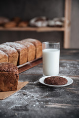 Bread with flour on wooden table with milk and cookie