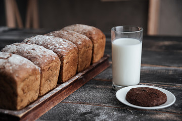 Bread with flour on wooden table with milk and cookie