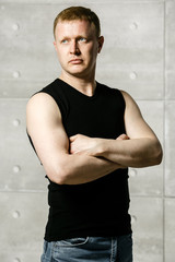 Obraz premium serious man on the background of concrete walls and metal pipes in a black shirt and jeans