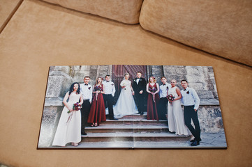 Two open pages of wedding book on sofa.