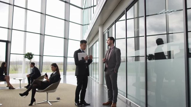  Businessmen talking as they walk through lobby of corporate office building
