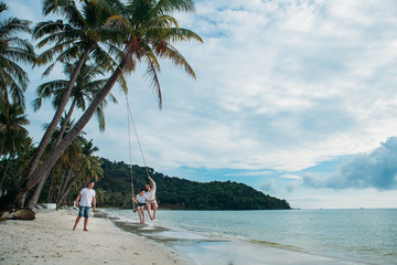 Family sit on Swing tropical beach