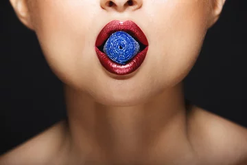 Nahaufnahmebild der Lippen des netten Mädchens, die Süßigkeiten mit den Zähnen halten. © Cookie Studio