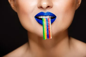 Nahaufnahmebild der bunten Lippen der sexy Frau, die Süßigkeiten halten. © Cookie Studio