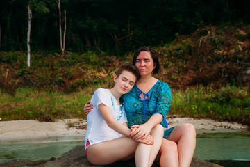 Young caucasian mother and daughter sitting on the beach phu quoc