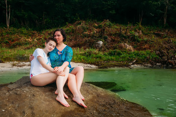 Young caucasian mother and daughter sitting on the beach phu quoc