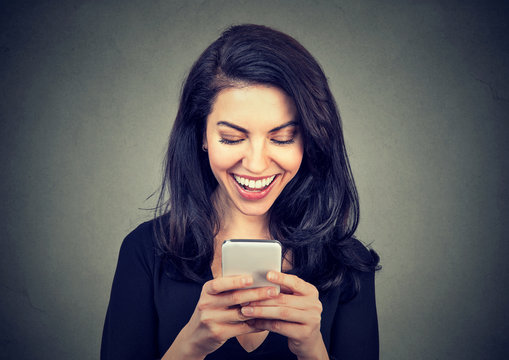 Laughing woman text messaging on smart phone having a pleasant chart conversation