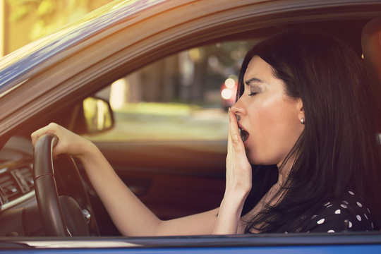 sleepy yawning woman driving her car after long hour trip.