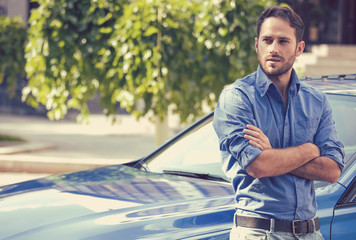 Handsome man standing in front of his car