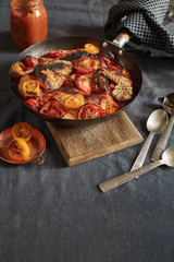 baked chicken parts with tomatoes and garlic in the frying-pan