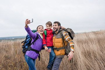 Happy family with backpacks taking selfie