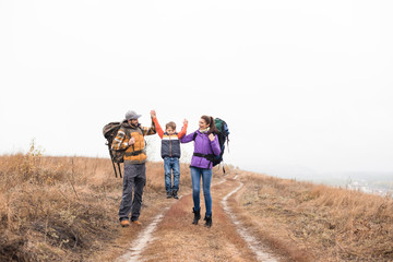 Obraz premium Happy family with backpacks holding hands