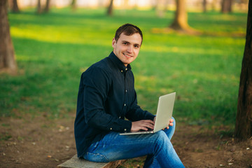 The young manager working on a laptop in the park. Lunch Break.