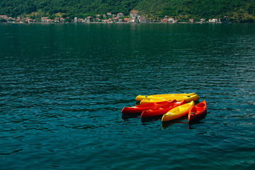Kayaks moored in the water. Empty kayaks without people. In the Bay of Kotor, in Montenegro.