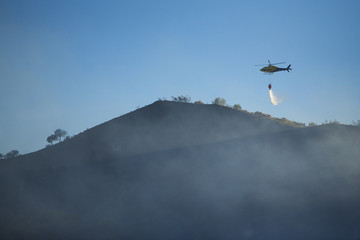 GRANADA, AUGUST 28: Fire fighting Helicopter, with bambi basket, during a fire fighting in the bush. August 28, 2014, Granada, Spain.