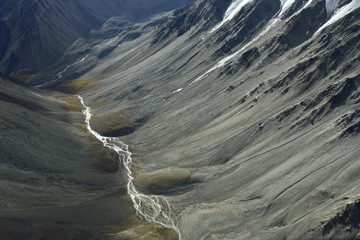 deep valley with a small creek between high mountains and a sunny spot © Christian