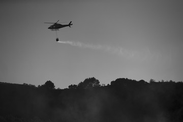 Fototapeta na wymiar GRANADA, AUGUST 28: Fire fighting Helicopter, with bambi basket, during a fire fighting in the bush. August 28, 2014, Granada, Spain.