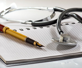 stethoscope, notebooks and pen on a white background