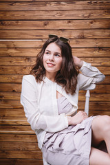 a young girl with long hair, white clothing, on a chair and wooden background