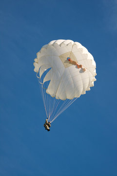 White parachute on background blue sky.