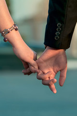Young couple holding hands. The glow of sunset. A symbol of love and fidelity.
