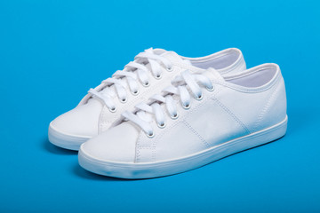 Pair of new white sneakers on blue background