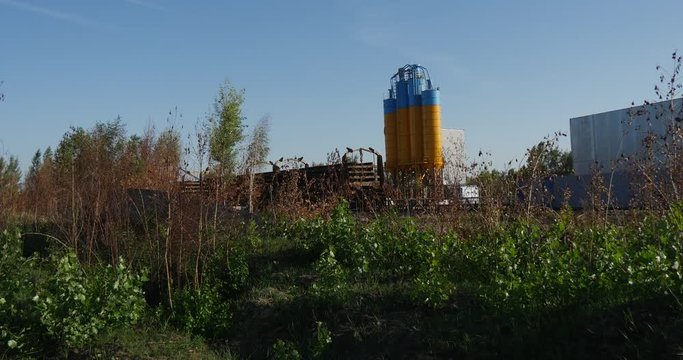 High Oil Storage Reservoirs Painted in Yellow and Blue Colors, Sticking Out From Some Wooden Fence, in Ukraine, in the Daytime in Summer